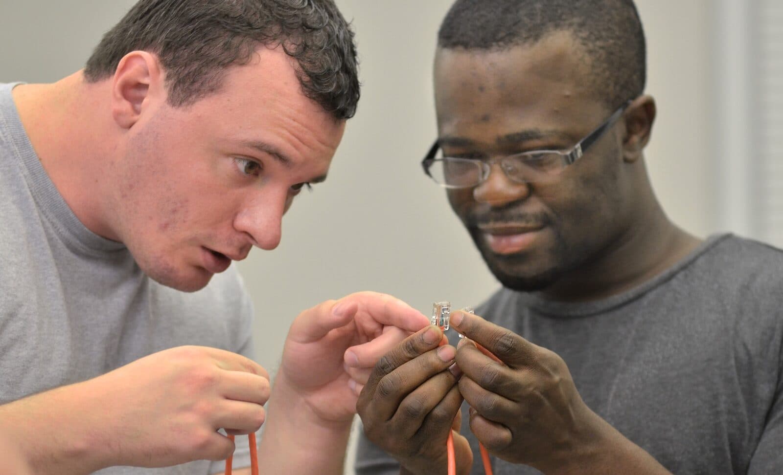 Two students wiring a network cable during a cybersecurity training session